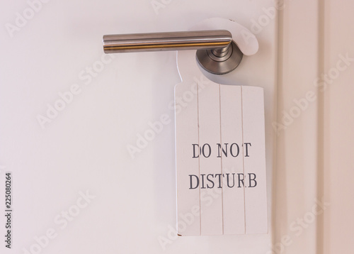 white do not disturb sign at restroom door. doorhanger made of wood with print on it.