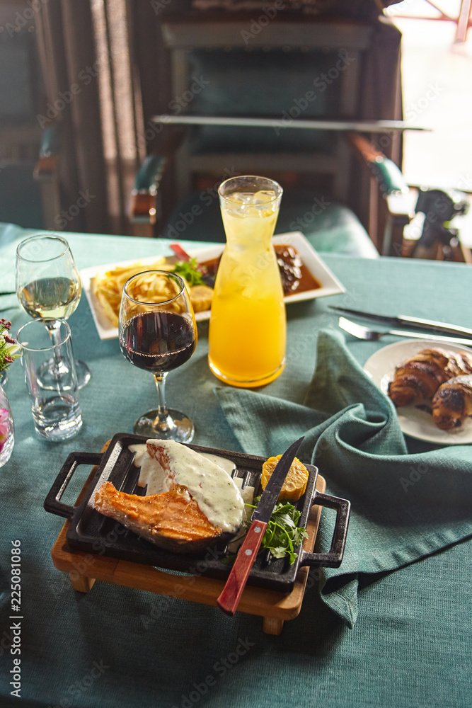 Steak from salmon with sauce and a decanter of a berry drink