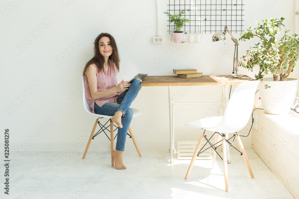 Technology and people concept - Young beautiful woman sitting at the white table with digital tablet Technology and people concept - Young beautiful woman sitting at the white table with digital tablet