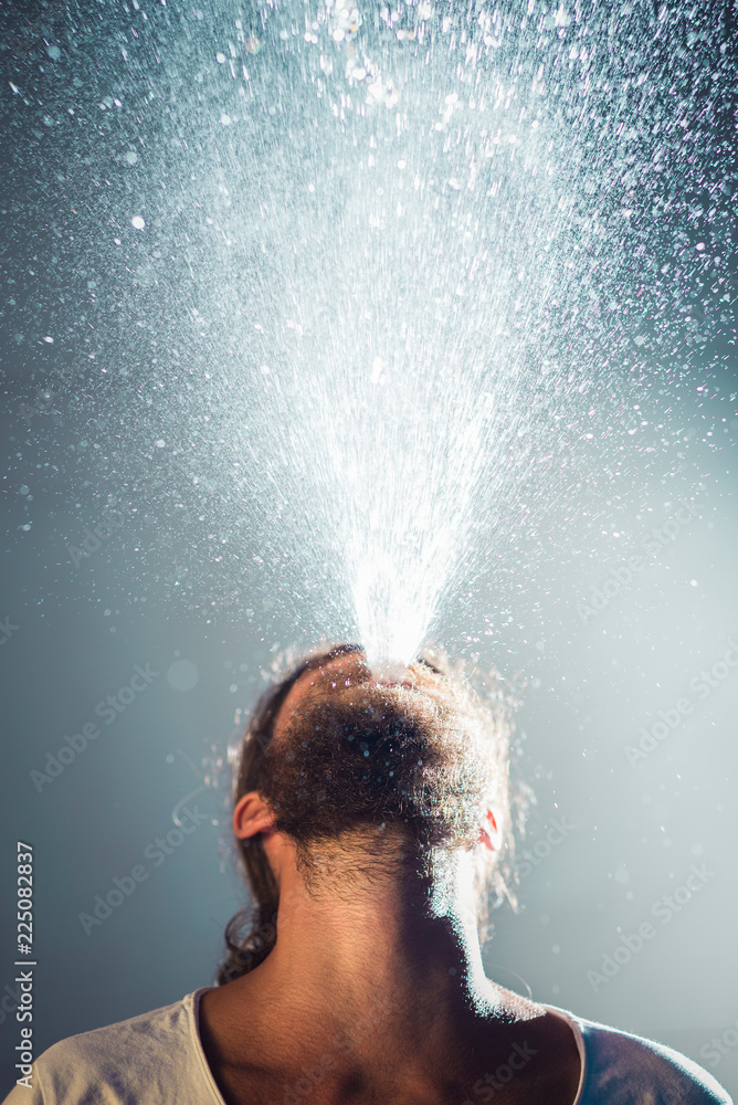 Young man blowing water from mouth Young man blowing water from mouth