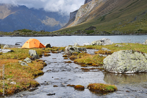 Arkhyz, Russia, Caucasus. The orange tent on the banks of Zaprudnoye lake in cloudy autumn day