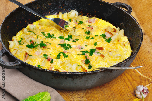 Traditional rustic omelette with bacon, pasta and greens .  Copy space