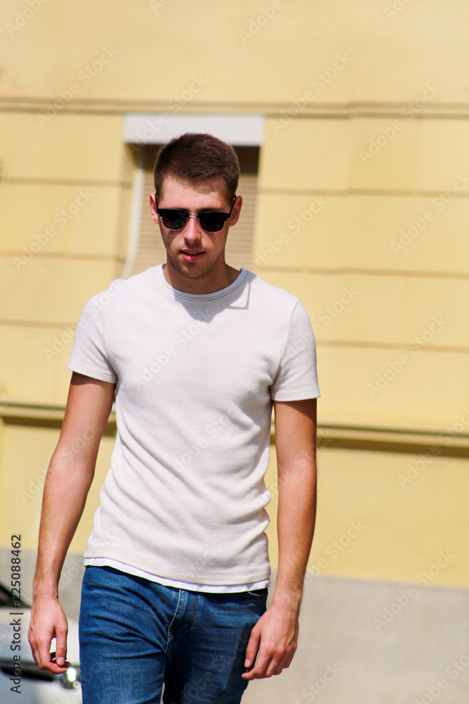 Man Summer Casual Fashion. Wearing a gray t shirt, casual short pants,  sunglasses, arms resting on a wooden stick, a young handsome guy is  standing by Stock Photo - Alamy