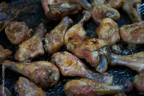Roasted chicken legs with spices on black tray background, close-up
