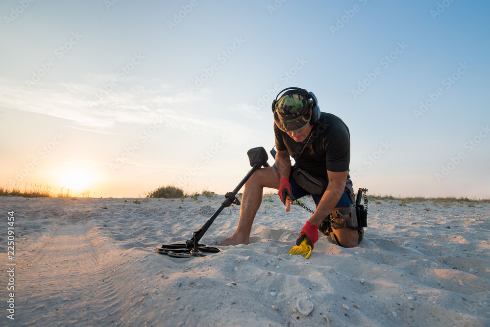 Man with a metal detector on a sea sandy beach - obrazy, fototapety, plakaty 