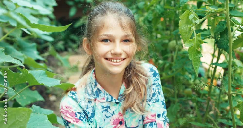 Portrait teenage girl harvesting cucumbers in the kitchen garden, smiling at camera Portrait teenage girl harvesting cucumbers in the kitchen garden, smiling at camera