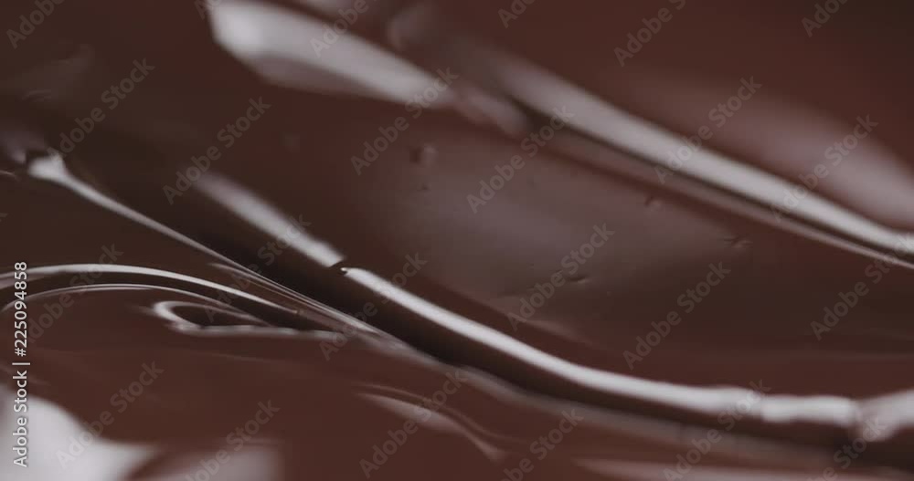 Slow motion closeup stirring melted dark chocolate from spoon Slow motion closeup stirring melted dark chocolate from spoon