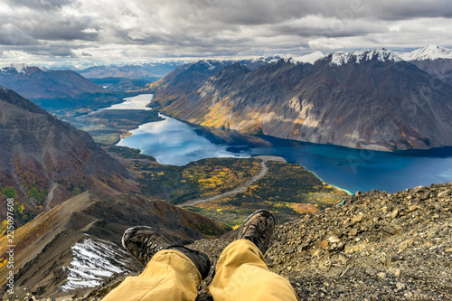 Adventure concept, resting male legs in front of the stunning landscape. Yukon, Canada