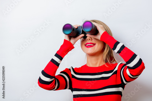 Portrait of a beautiful white woman in red sweater with binocular on white background, isolated.