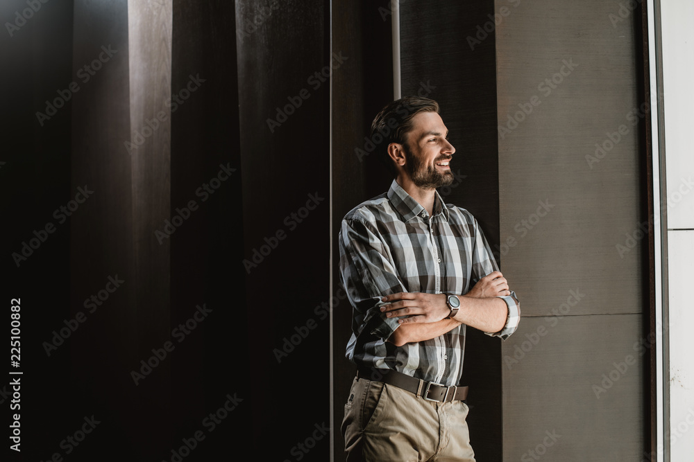 Happy attractive guy is spending good time inside. He is leaning against wall and looking away with joy. Copy space in left side Happy attractive guy is spending good time inside. He is leaning against wall and looking away with joy. Copy space in left side