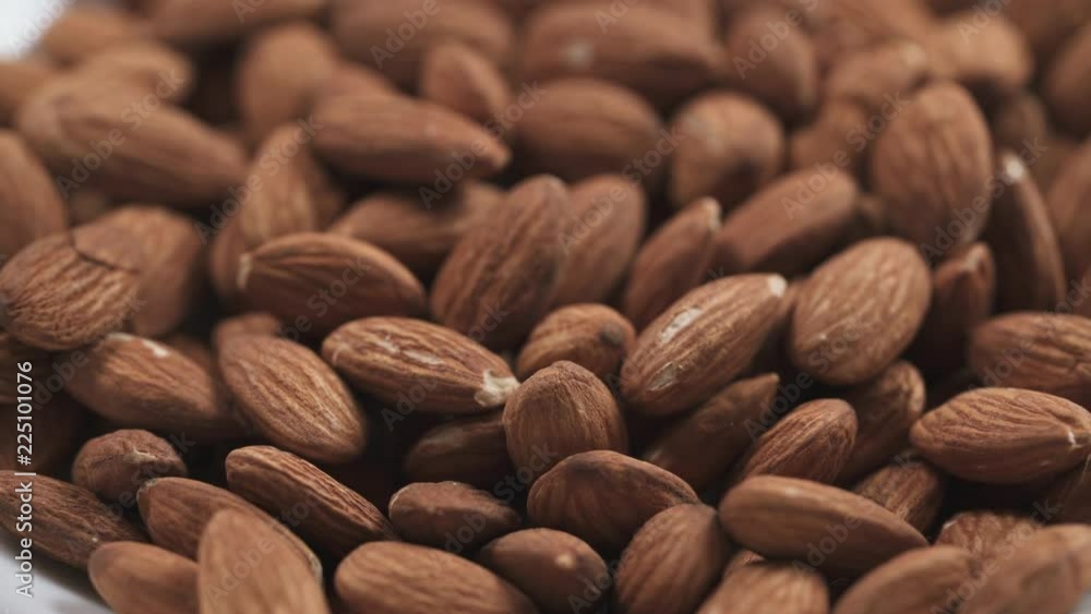 closeup roasted almonds falling in white bowl closeup roasted almonds falling in white bowl