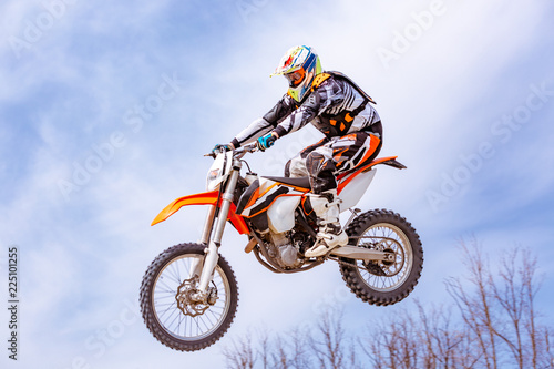 Fototapeta Naklejka Na Ścianę i Meble -  racer on a motorcycle in flight, jumps and takes off on a springboard against the snowy mountains