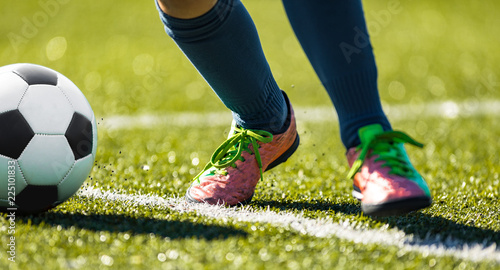 Close up soccer football kick the ball. Feet of footballer running and kicking the soccer ball on green grass photo