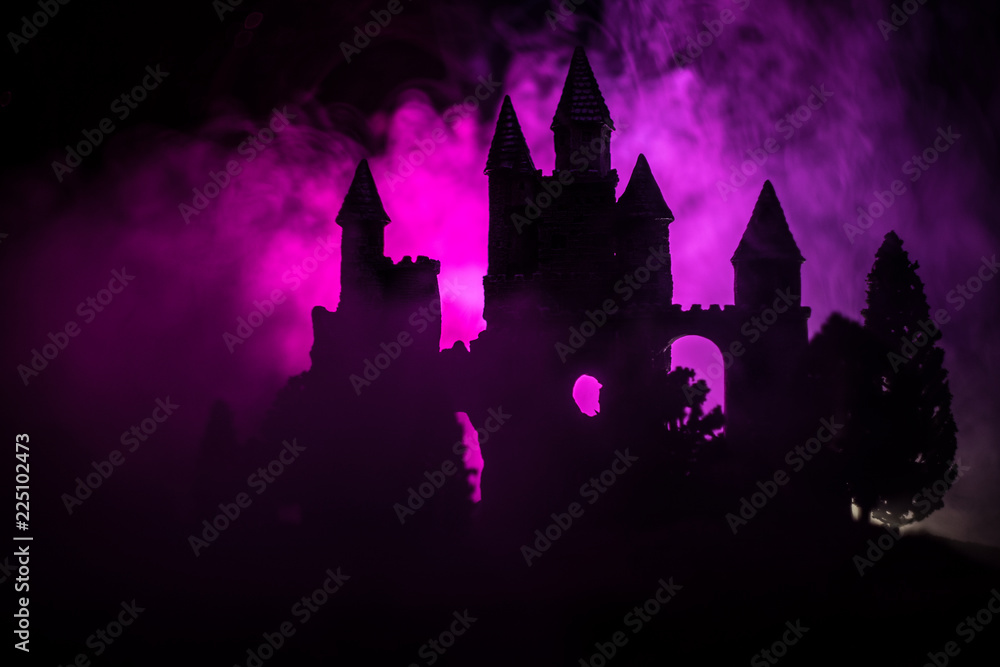 Mysterious medieval castle in a misty full moon. Abandoned gothic style old castle at night