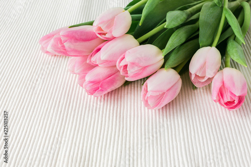 Fototapeta Naklejka Na Ścianę i Meble -  Pink tulips on white tablecloth. Copy space, top view