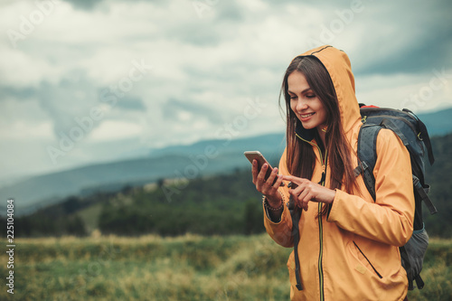 Nice young woman using her mobile phone while enjoying her weekend in the mountains