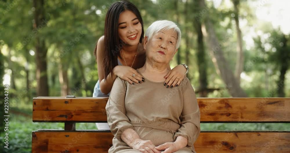 Teen asian granddaughter hugging and kissing her happy mature