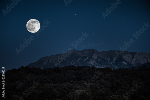 Fototapeta Naklejka Na Ścianę i Meble -  Mountain Road through the forest on a full moon night. Scenic night landscape of dark blue sky with moon. Azerbaijan