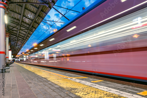 Highspeed train arrives to the station platform at evening time.