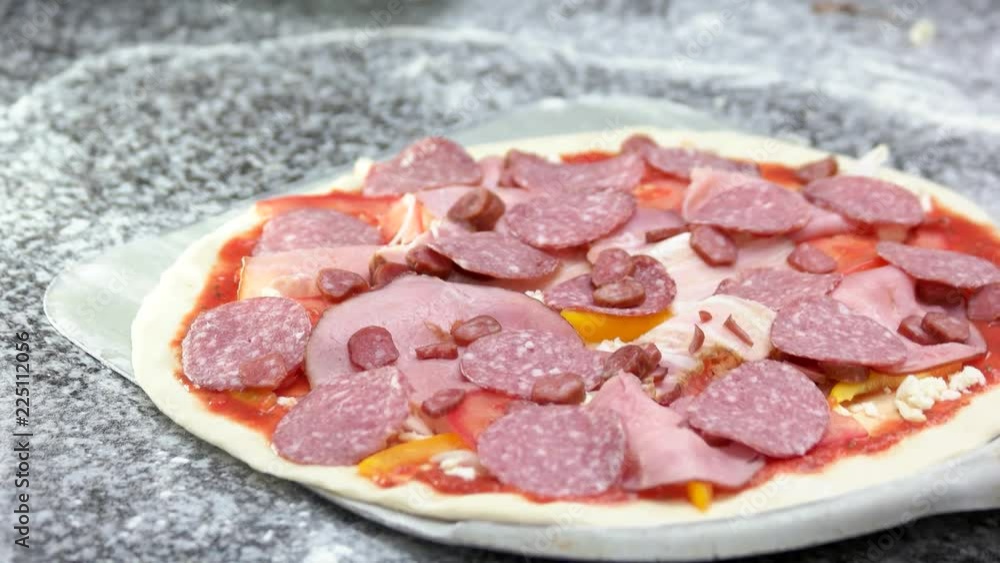 Uncooked Italian meat pizza. Thin crust, salami and pepperoni. Stock