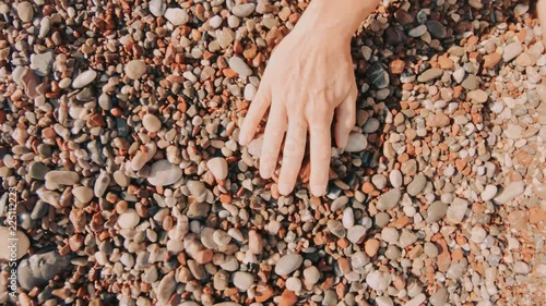 A Female Hand Stroking Over Wet Colorful Sea Pebbles By The Seashore In Slow Motion.