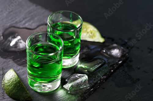 Two glasses of absinthe with melted ice and slices of lime