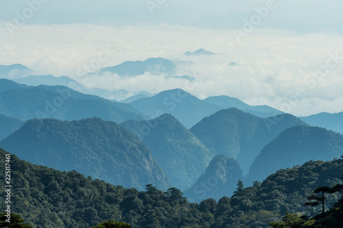 view of the far away mountain range covered in thick white cloud under hush sun light in the hazy morning © Yi