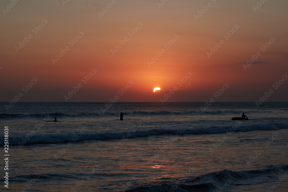 A beautiful sunset on a sea with surfers