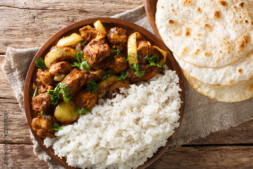 Traditional recipe for Indian chicken do pyaza (dopiaza) with onion and spice and garnish of rice close-up on a plate with flatbread. horizontal top view photo