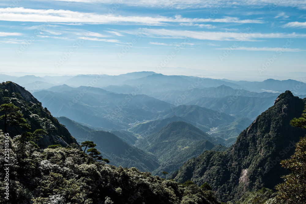 forest covered valley floor covered in haze cause by the rising sun above the cloud