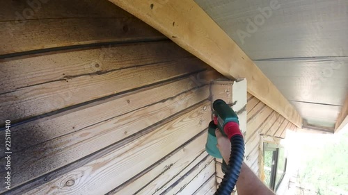 Painting of the wooden house from a bar by aerosol black paint at height in dry summer weather outside 