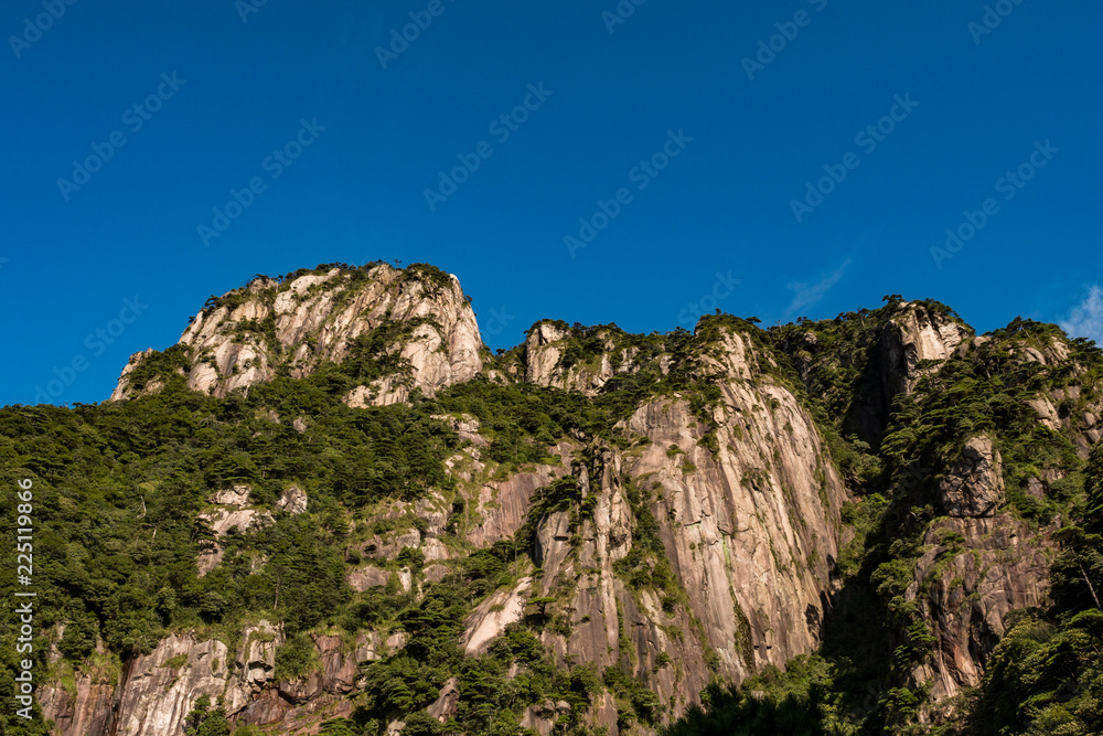 unique peaks of Mt. SanQiang covered in green under cloudy blue sky