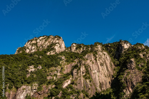 unique peaks of Mt. SanQiang covered in green under cloudy blue sky © Yi