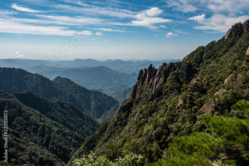view of the Mount SanQiang valley floor covered with green under cloudy blue sky on a sunny day