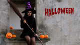 Young woman in witch Halloween costume is sitting and hold a witch's bloom