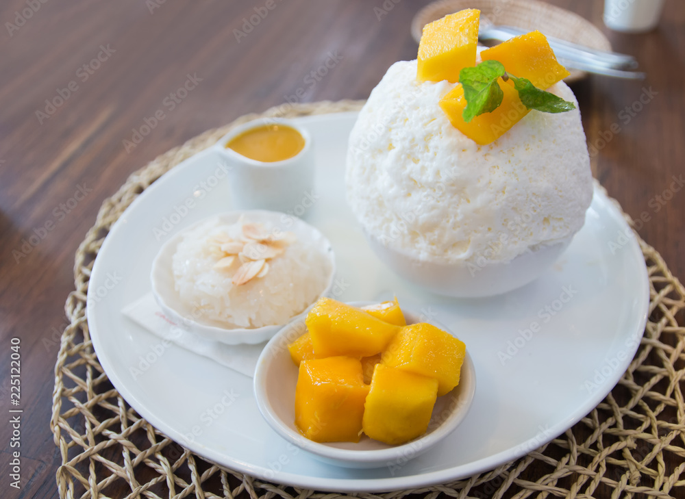Set of Korean ripe mango Bingsu, sweetened condensed milk dessert, sticky rice, serving on white ceramic plate. Unhealthy dessert concept Set of Korean ripe mango Bingsu, sweetened condensed milk dessert, sticky rice, serving on white ceramic plate. Unhealthy dessert concept