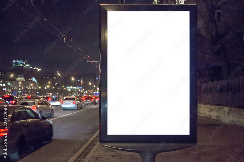 Mock up of blank white vertical light box in a city near traffic jam at night Mock up of blank white vertical light box in a city near traffic jam at night