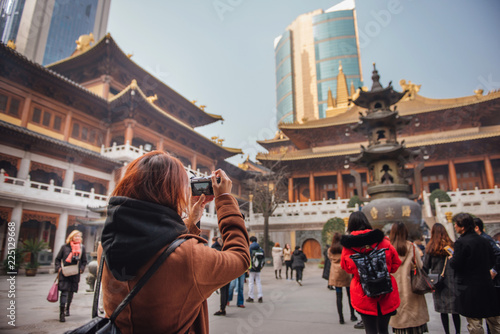 Canvas Print Young tourist woman taking photo picture at jing'an temple in downtown area of shanghai, china