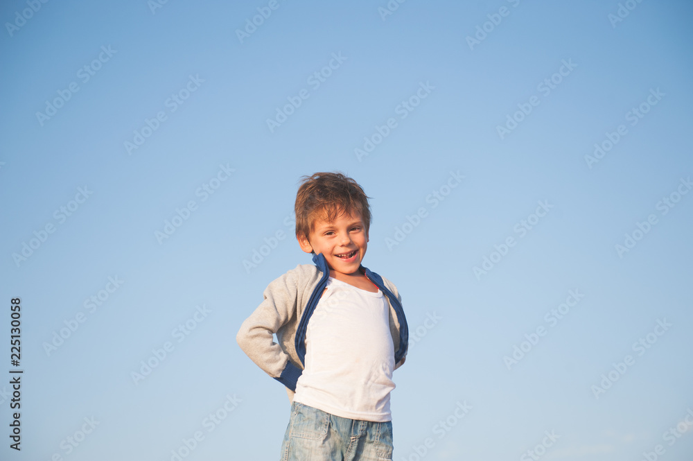 happy delightful smiling little boy in sweater on blue sky background happy delightful smiling little boy in sweater on blue sky background