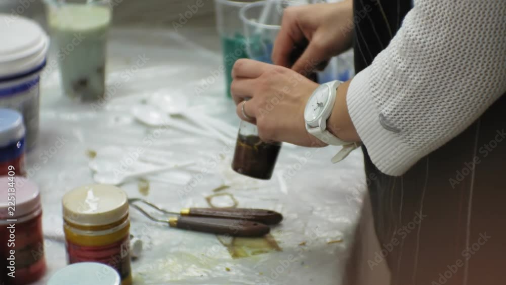 women in an art studio mix paints and draw on canvas in fluid art technique women in an art studio mix paints and draw on canvas in fluid art technique