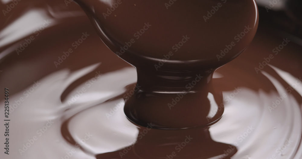 closeup pouring melted dark chocolate from spoon closeup pouring melted dark chocolate from spoon