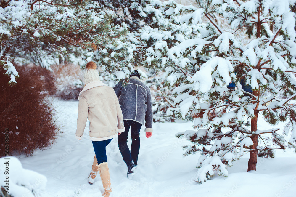 Lifestyle winter portrait of romantic couple walking and having fun in snowy forest