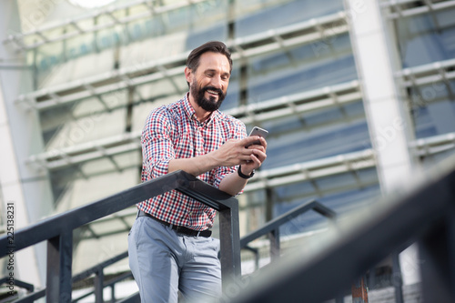 Joyful bearded man using his mobile phone outdoors