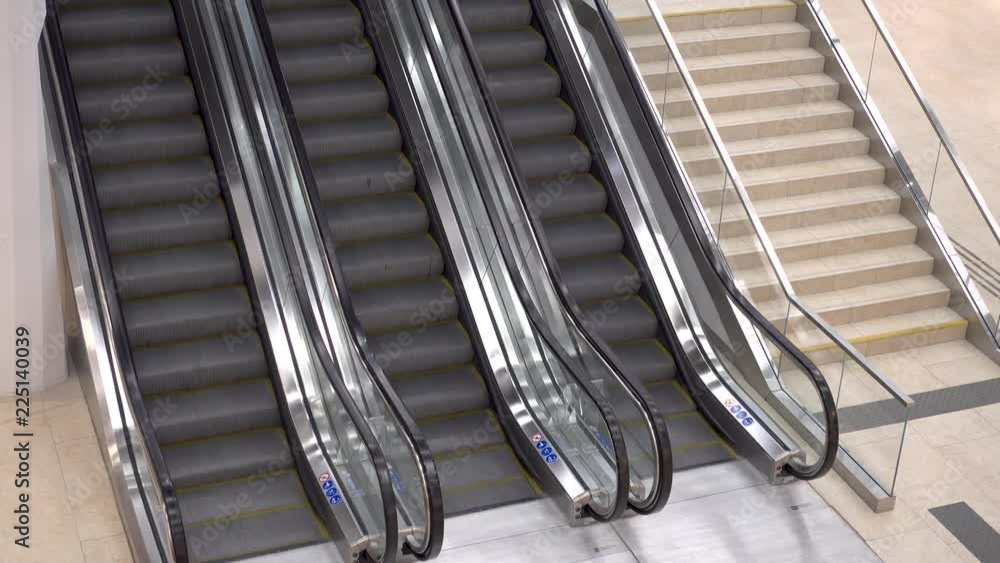 Three escalators in the shopping Mall. Escalators moving staircases in motion no people. The image contains a small noise. 4K