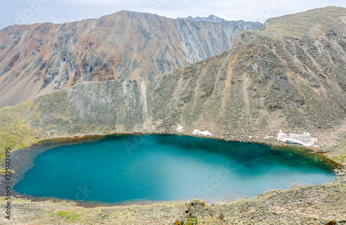 Blue lake with a lot of colors pasted in circus of mountains. There is a small glacier and water comes from it. Altay.