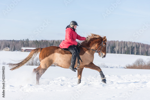 Woman on a galloping horse during winter.