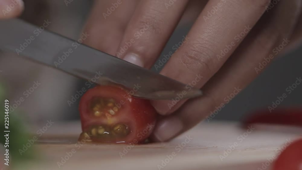 The chef is cutting red tomatoes on a butcher The chef is cutting red tomatoes on a butcher