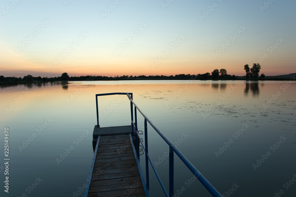 Bridge made of planks and a metal railing on the lake. Staw, Poland