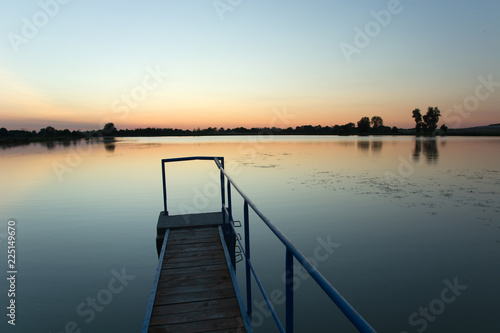 Bridge made of planks and a metal railing on the lake. Staw, Poland