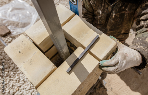 The worker is laying bricks on the fence